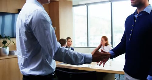 Executives shaking hands in office