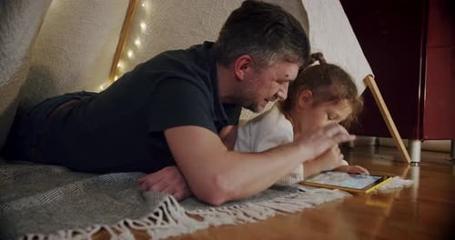 Father and Child Enjoying Tablet Inside Blanket Fort