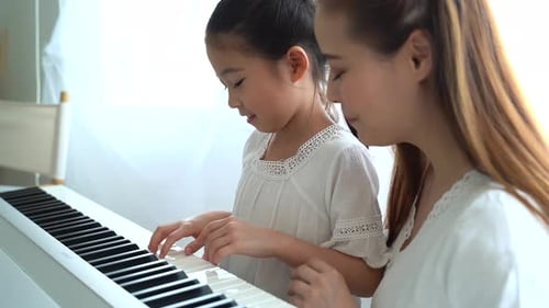 Young Girl and Woman Play Piano Together