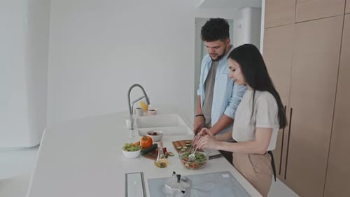 Young Couple Cooking Fresh Salad Together at Home