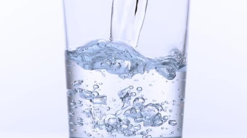 980034 Se vierte agua en un vaso sobre un fondo blanco, Cámara lenta