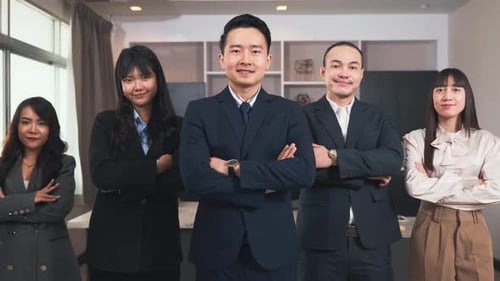 Successful group of business people smiling while standing with crossed arms in office