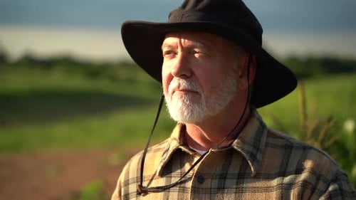 Close up portrait of senior caucasian good looking wise man farmer in a hat looking at the side, tur