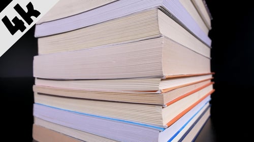 Books Pile Up On Reflective Black Surface