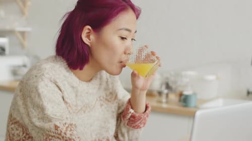 Woman with Magenta Hair Works on Laptop at Home