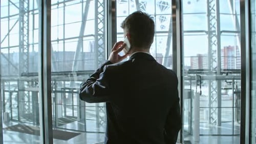 Young Adult Talking on Phone in Glass Elevator