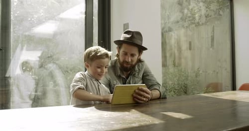 Boy and Man Using Tablet Together Indoors