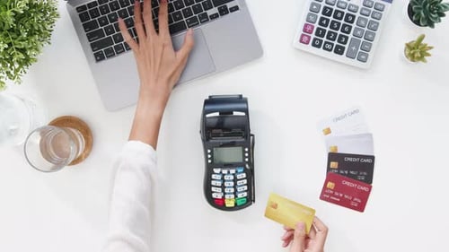 Top view of Asia lady using laptop online shopping with credit card pay the bill by payment terminal