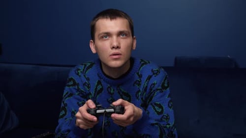 Front View of an Excited Caucasian Man Playing Video Games and Using Joystick Controller. Tired Man