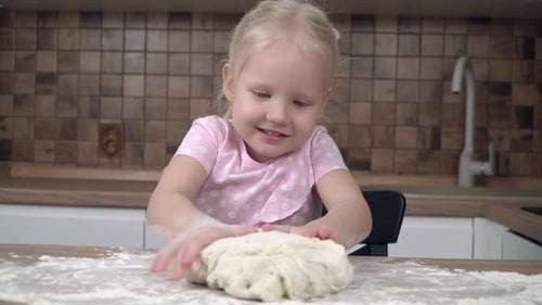 Happy Child Kneading Dough in the Kitchen