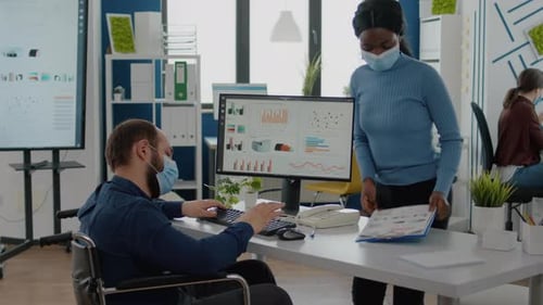 Divers collègues masqués travaillant dans le respect de la distance sociale