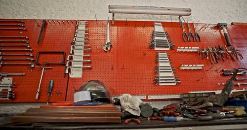 Working tools hanging on red wall and workbench in panning right view