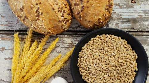 Wheat grains with bread buns, oats and spoon full of flour