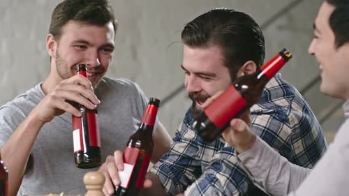 Three Young Men Drinking Beer and Laughing Together