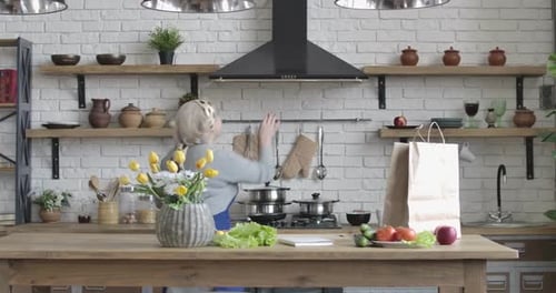 Nice Caucasian Mature Woman Entering Kitchen, Turning on Range Hood and Deciding What To Cook