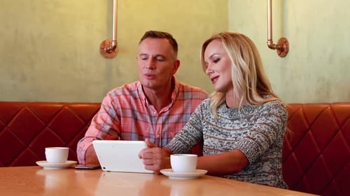 Couple Using Tablet Together in Modern Cafe