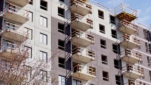 Construction de la maison en étage élevé par une journée ensoleillée, le travailleur dans un casque de protection fait une façade