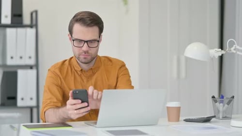 Young Man Using Smartphone in Office