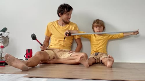 Man and Boy Install Laminate Flooring Together