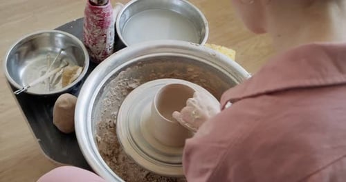 Potière assise et fabrique une tasse sur la roue à poterie. Femme fabriquant un Item en céramique. Poterie