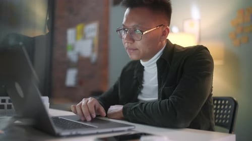 Young Adult Typing at Desk in Office at Night