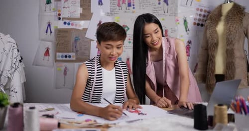 Portrait of Two fashion designer women working in studio