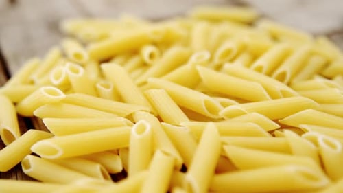 Pile of Uncooked Penne Pasta on Wood Surface