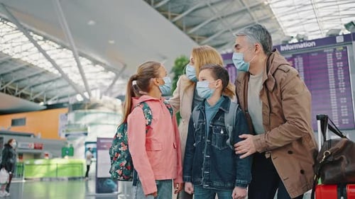 Excited Parents Standing with Children at Airport Looking Around and Enjoying Trip Wearing