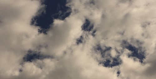 Fluffy White Clouds Drifting Across Blue Sky