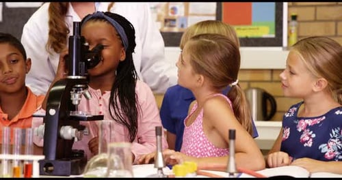 Teacher assisting school kids with experiment in laboratory