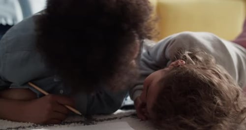 Two Girls Drawing Together on Carpet Indoors