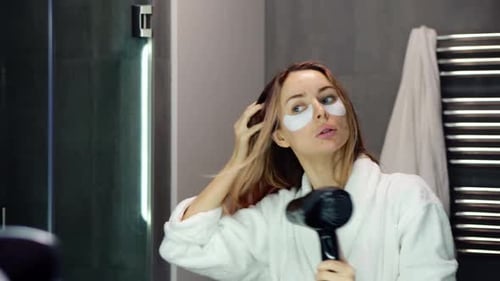 Woman Dries Hair in Mirror Wearing Robe