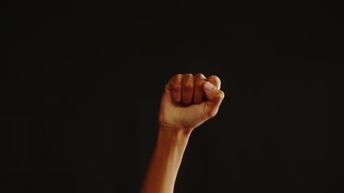 Raised Fist Arm Symbol Against Black Background