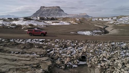 Flying backwards over dirt road as truck drives through the landscape