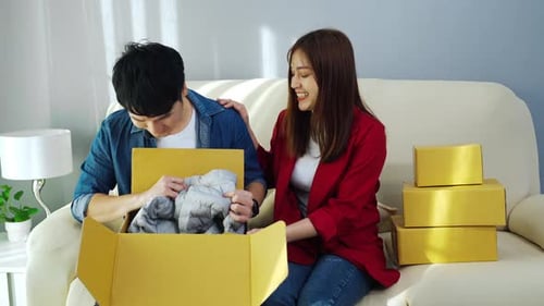 happy couple open cardboard parcel box in the living room at home, purchase on online store