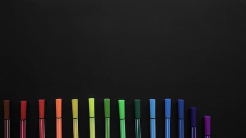 School Markers of Different Colors Are Located on the Black Surface. Stop Motion Animation with