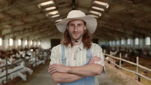 Positive Male Farmer in Uniform Standing at Ranch with Goats
