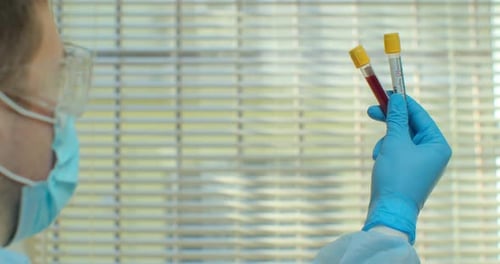 Medical Professional Examining Blood Samples in Test Tubes