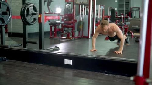 Mann macht einen perfekten Sprung Push Up, während er es vor einem riesigen Spiegel tut
