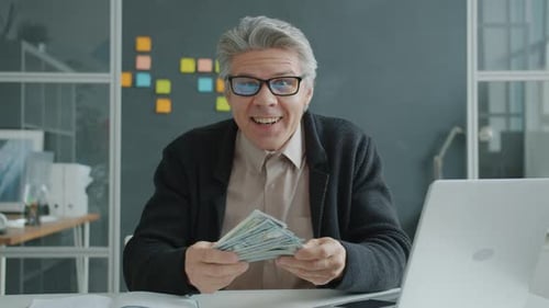 Zeitlupe eines erfolgreichen Unternehmers, gutaussehender reifer Kerl, der Geld wirft und Spaß im Büro hat