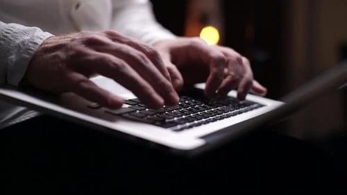 Close-up of Man Hands Is Working Typing Use Laptop Computer at Dark Home Office, on Knees.