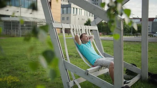 Un jeune homme repose sur un banc par une journée ensoleillée. Mouvement de caméra