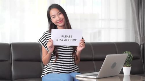 Woman Holds Stay Home Sign on Sofa