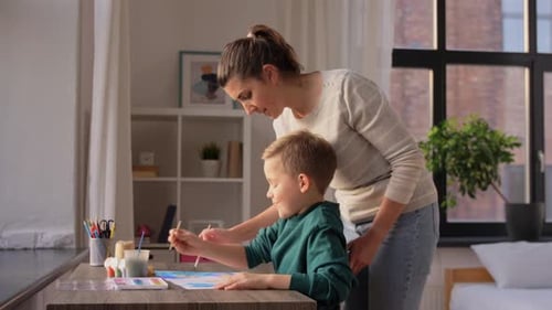 Mother Helping Son Paint Together Indoors