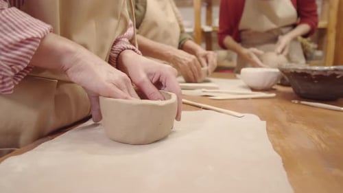 Hände von drei anonymen Töpferinnen bei der Herstellung von Tonschalen in Werkstatt