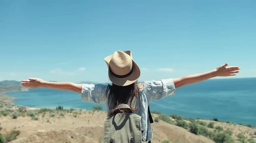 Woman Traveler with Arms Outstretched Overlooking Ocean