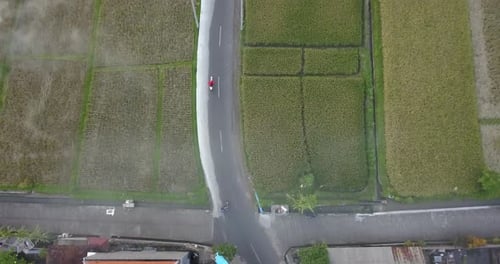 Aerial drone view of a man riding his motocross motorcycle on a road in Bali.