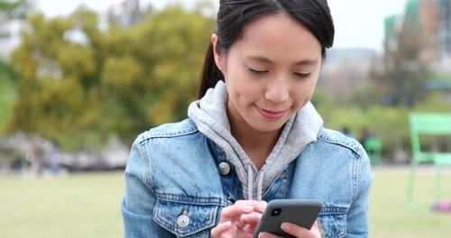 Young woman use of mobile phone at outdoor park