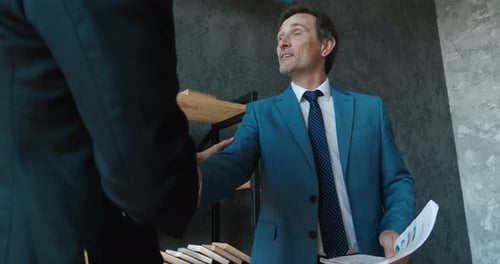 Two Mature Businessmen Shake Hands in a Modern Office
