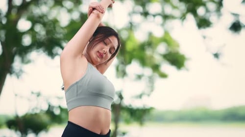 Young asian woman stretching arms before exercising summer park outdoor in morning